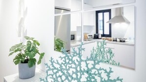 Eine moderne Küche mit weißen Schränken, einem großen Fenster und einem Blumentopf.