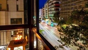 Blick aus einem Fenster auf eine belebte Straße bei Nacht, mit Ampeln und Gebäuden im Hintergrund.