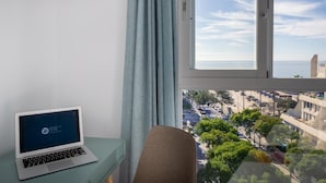 Een laptop op een bureau, met uitzicht op een stadsgezicht door een raam.