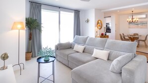 Een moderne woonkamer met een grijze hoekbank, een staande lamp en een plafondventilator.