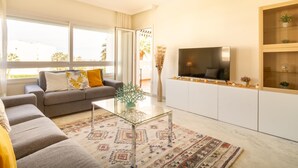 A modern living room with a sofa, a glass coffee table, a flat-screen TV, and a decorative vase. - Banus Playa Rocio Sea Views (Puerto Banús)