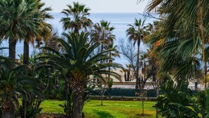 A landscaped garden with palm trees, a pool, and a view of the sea. - Banus Playa Rocio Sea Views (Puerto Banús)