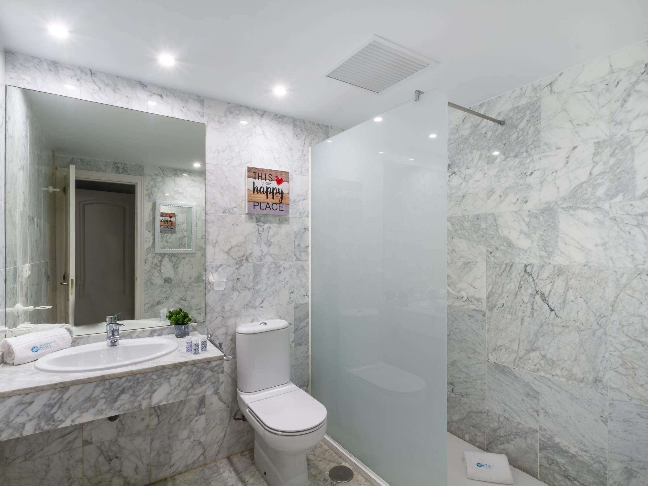 Ein Badezimmer mit Marmorwaschbecken, Toilette und Dusche.