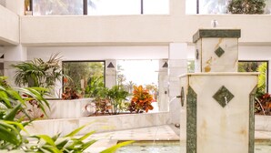 A spacious indoor area with a central fountain, surrounded by various potted plants and a tiled floor. - Banus Playa Rocio Sea Views (Puerto Banús)
