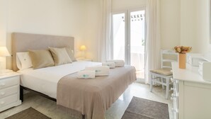 Habitación de hotel con una cama grande, un escritorio, una silla, una lámpara y vistas al exterior.