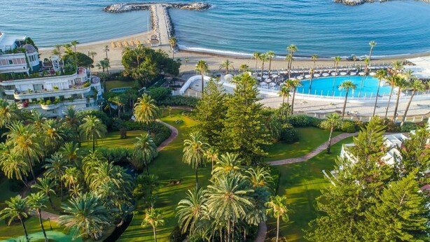 A resort with a pool, palm trees, and a beach. - Banus Playas del Duque Beachside Residential (Puerto Banús)