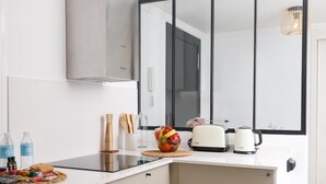 Une cuisine moderne avec un plan de travail blanc, un grille-pain, une bouilloire et un saladier rempli de fruits.