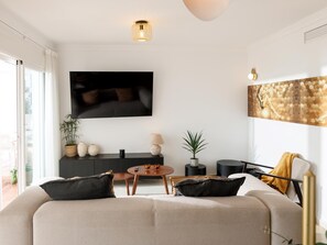 En moderne stue med sofa, sofabord, fjernsyn og kunst på væggen.