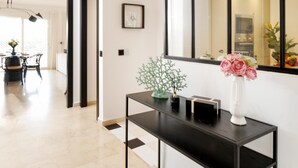 Un intérieur moderne comprenant un coin repas, une console surmontée d’un vase et un grand miroir qui reflète la pièce.