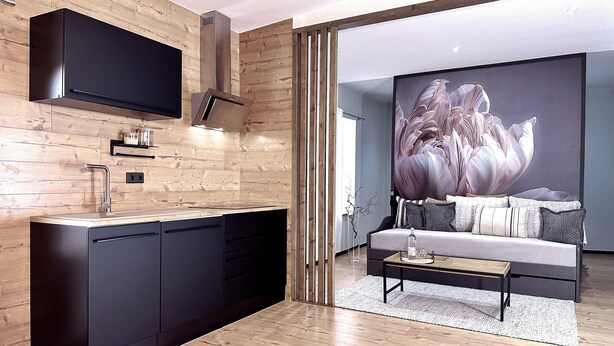 A modern kitchen with a built-in stove, a flat-screen TV, and a wooden backsplash.