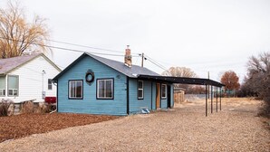 A single-story blue house with a covered porch, a chimney, and a gravel driveway. - 2 bed 1 bath cottage home (Price)
