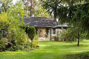 Ein traditionelles Haus mit Ziegeldach, umgeben von üppigem Grün und einem gepflegten Rasen.