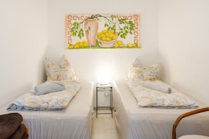 Une chambre avec deux lits, une table de chevet, une lampe et un tableau au mur.