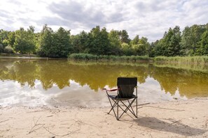 Une chaise au bord d’un lac paisible, avec des arbres en arrière-plan.