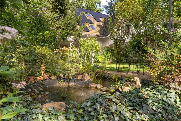 Ein Garten mit Teich, Steinen und verschiedenen Pflanzen.