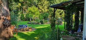 A garden with a stone bench, a tree, and a pergola covered in vines.