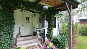 Une maison dotée d’un porche abrité, d’un escalier menant à la porte et d’un luminaire suspendu.