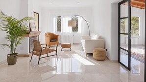 Un salon moderne avec un canapé blanc, deux fauteuils en osier, une lampe sur pied et une grande plante en pot.