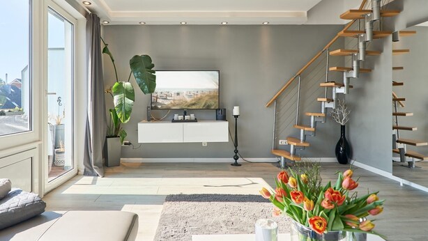 A modern living room with a large window, a staircase, and a view of the outdoors.