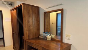 A wooden vanity with a mirror, a cabinet, and a small table with toiletries. - Budget Stars Hotel (Chiang Mai)