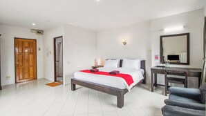 A hotel room with a bed, a desk, a chair, a mirror, and a door. - Budget Stars Hotel (Chiang Mai)