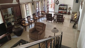 A spacious living room with a high ceiling, a staircase, and a view of the outside. - The Reds Heritage.
Spacious rooms, vast gardens with a refreshing pool. (Kochi)