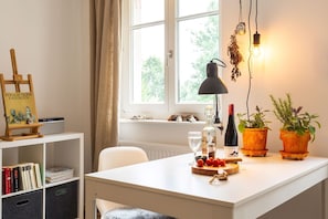 Een goed verlichte kamer met een wit bureau, een schilderij, een lamp en potplanten.