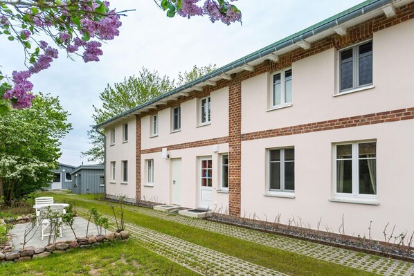 Edificio residencial de dos pisos con fachada de ladrillo y detalles blancos.