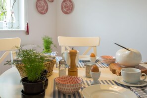 Et spisebord med forskelligt bestik, en potteplante og en hvid stol.