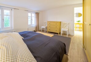 Et soveværelse med en seng, et skrivebord, en stol og et lille bord.