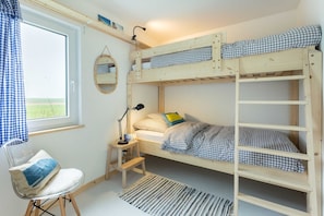 Habitación con literas, escritorio, silla y ventana con cortinas.