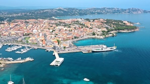 An aerial view of a coastal town with a marina, buildings, and a lighthouse.