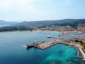 Stroll along the marina, where boats like Maddalena Linea await, surrounded by the town's charming buildings and lush greenery.