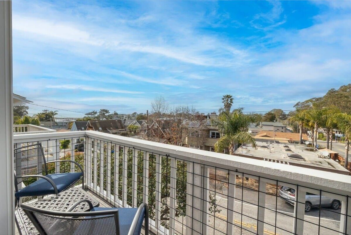 A balcony with a metal railing, a chair, and a table.