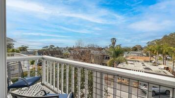 A balcony with a metal railing, a chair, and a table.