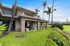 A two-story house with a covered patio, outdoor seating, and a well-maintained lawn.