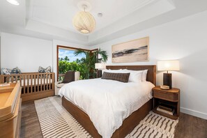 Une chambre à coucher avec un grand lit, une table de chevet, une lampe de chevet, une vue sur l’extérieur et un berceau en bois.