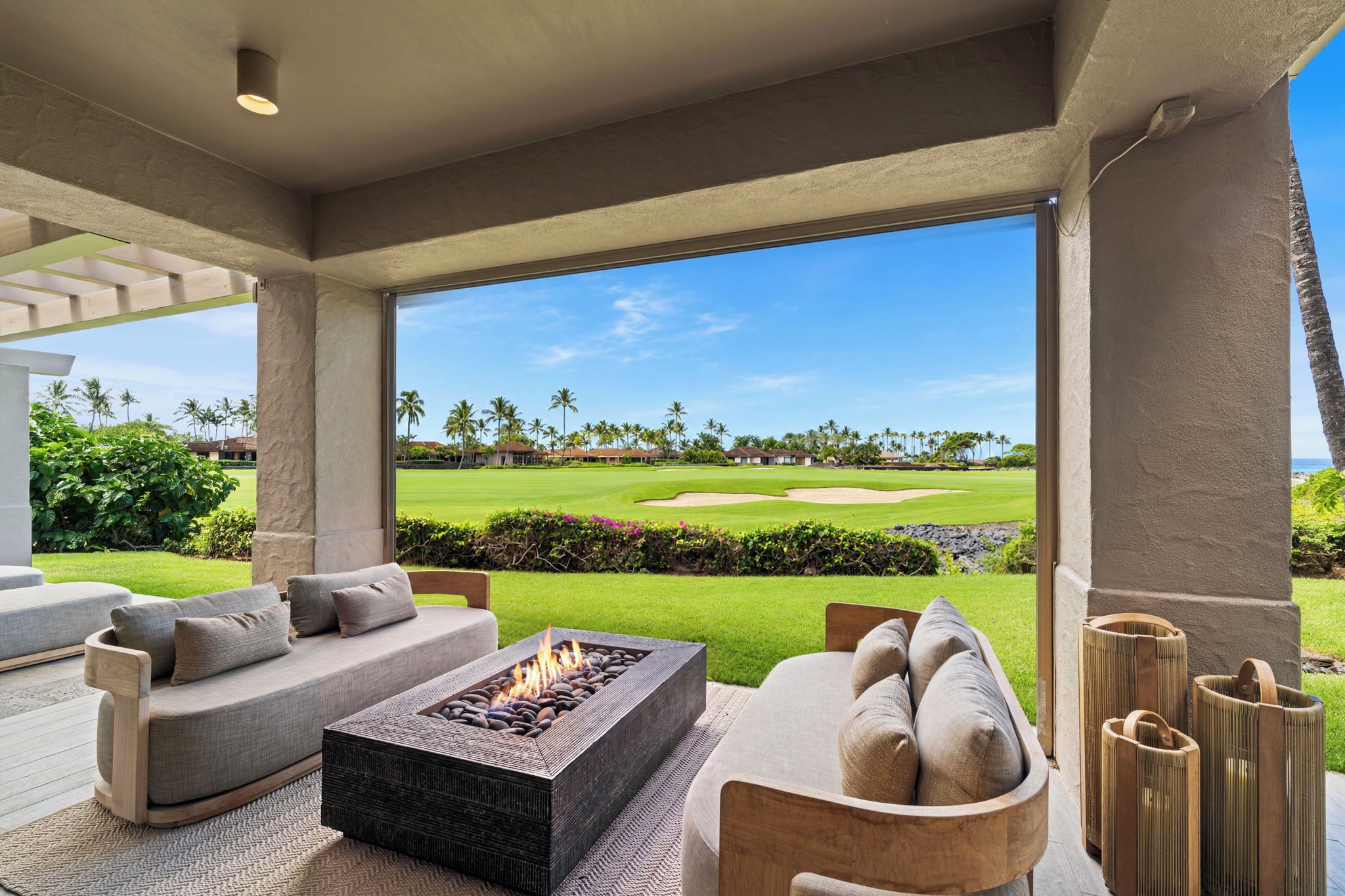 A modern outdoor seating area with a fire feature, overlooking a golf course.