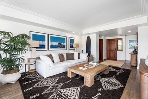 Un salon moderne avec un canapé blanc, une table basse et une grande plante en pot.