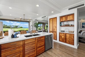 A modern kitchen with a large island, wooden cabinets, and a view of a golf course.