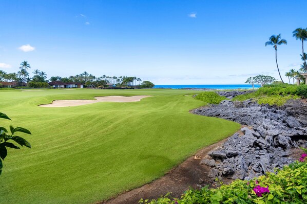Un parcours de golf offrant une vue dégagée sur l’océan, entouré d’une végétation tropicale et sous un ciel clair.