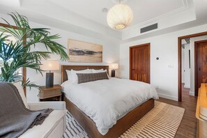 Une chambre à coucher avec un grand lit, des lampes de chevet, une plante en pot et un tableau au mur.