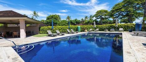 A swimming pool with lounge chairs and a covered seating area.