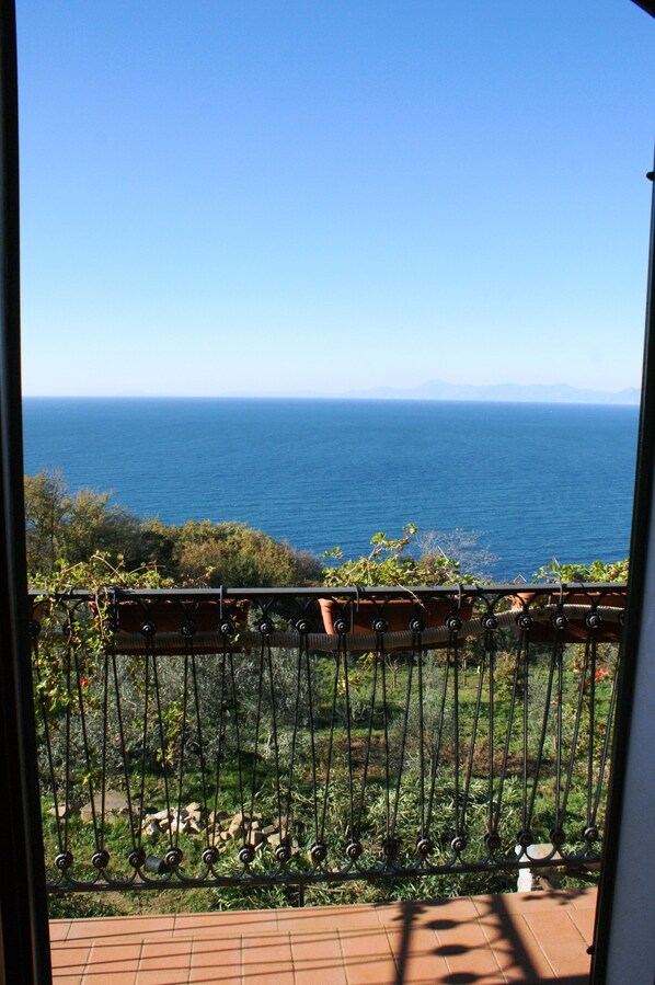 A balcony with a view of the sea and distant mountains.