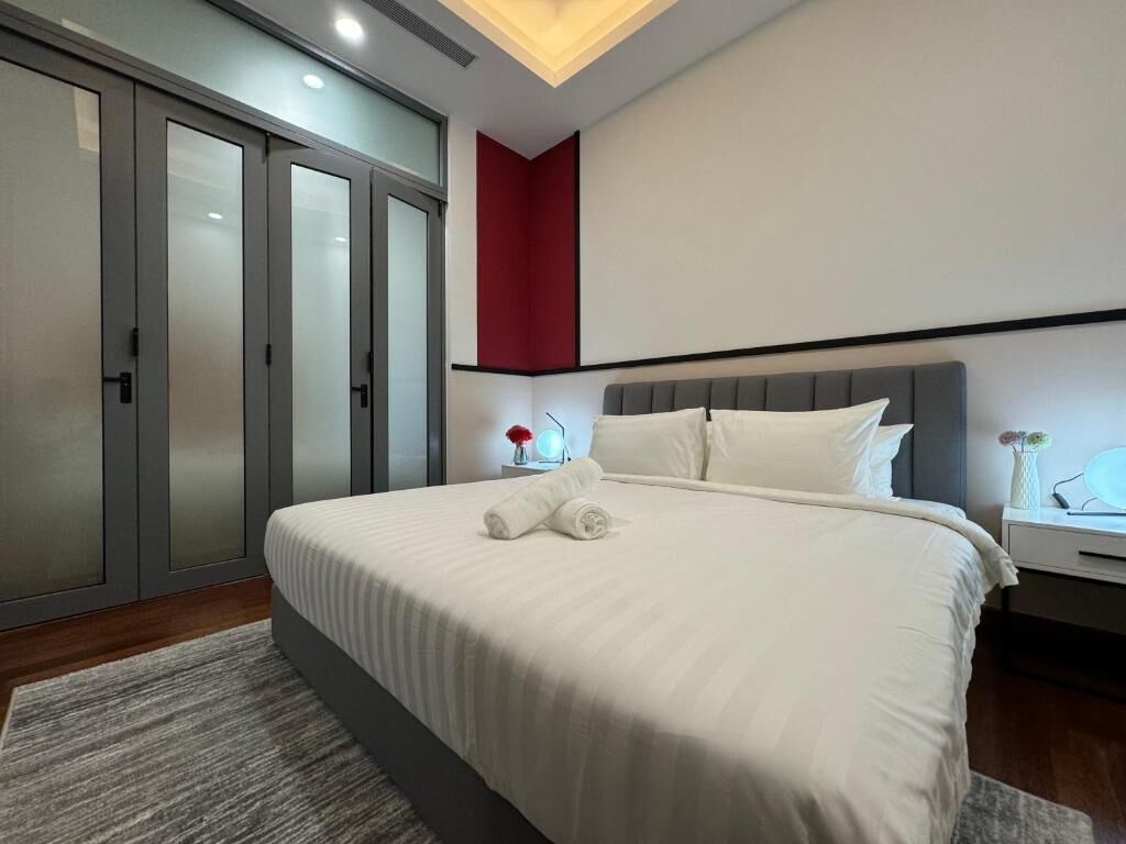 A modern bedroom with a large bed, a nightstand, and a wardrobe.