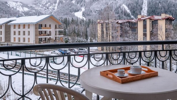 A balcony with a table, chairs, and a tray with cups and saucers. - Apt central proche des Pistes + Parking & Pool (Chamonix-Mont-Blanc)