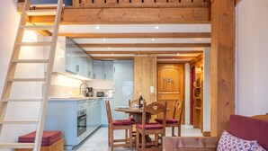 A loft-style room with a kitchen, dining area, and a red sofa. - Apt central proche des Pistes + Parking & Pool (Chamonix-Mont-Blanc)