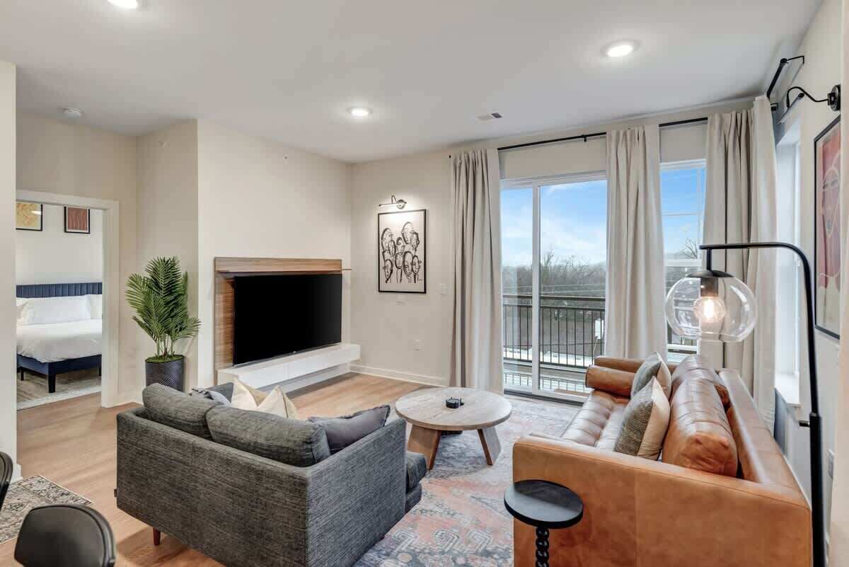 A modern living room with a sofa, a coffee table, a TV, and a fireplace.