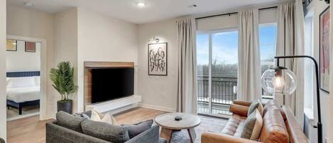 A modern living room with a sofa, a coffee table, a TV, and a fireplace.