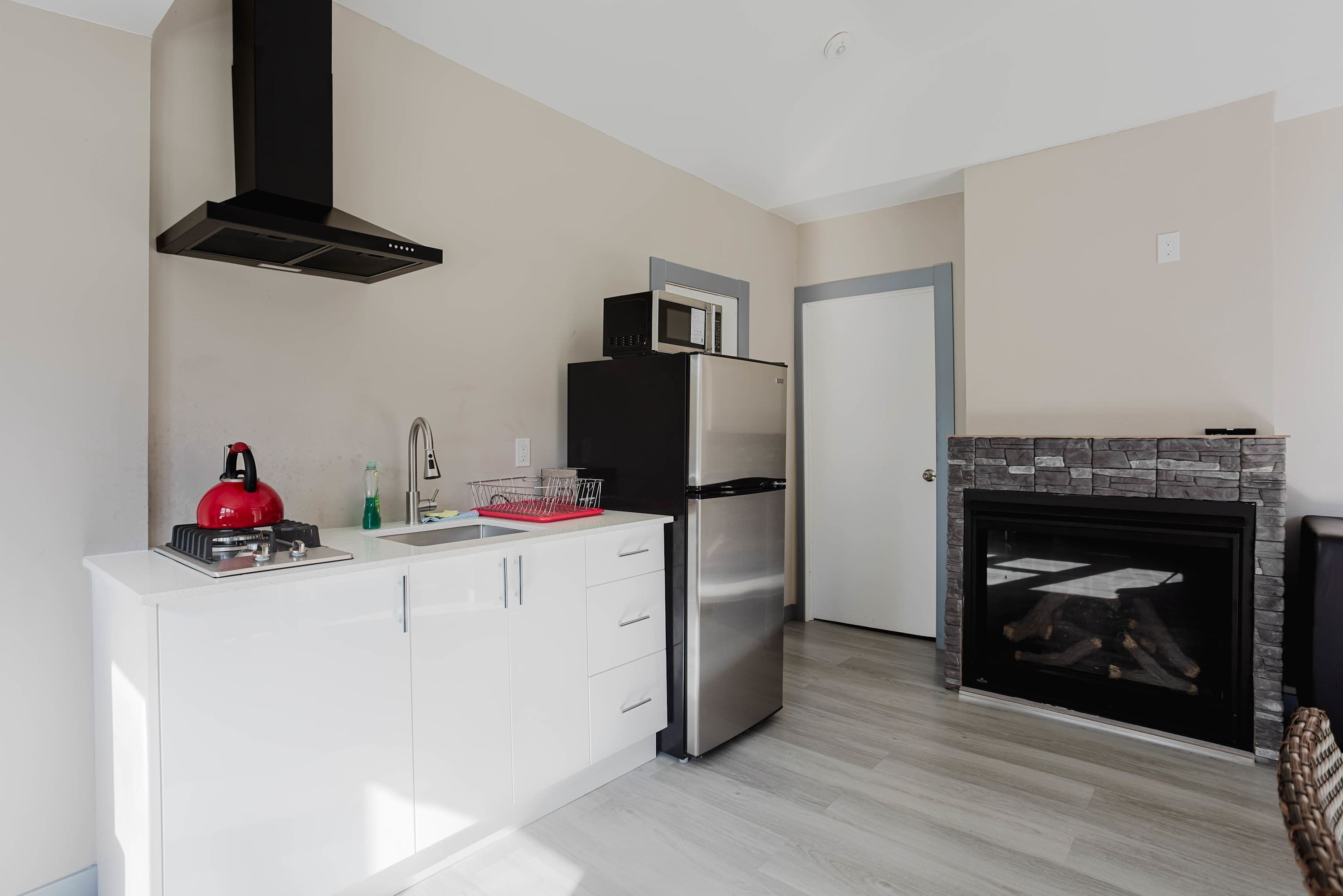 Een koelkast, een magnetron, een kookplaat, kookgerei, borden en bestek